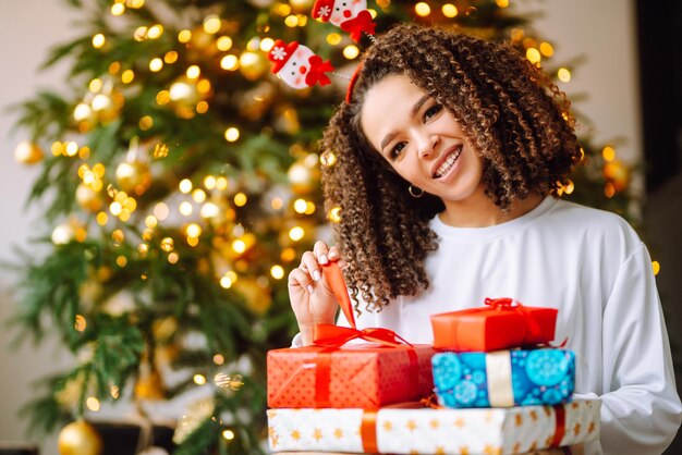 Retrato de jovem com chapéu de Papai Noel com presente na árvore de Natal Natal Ano Novo