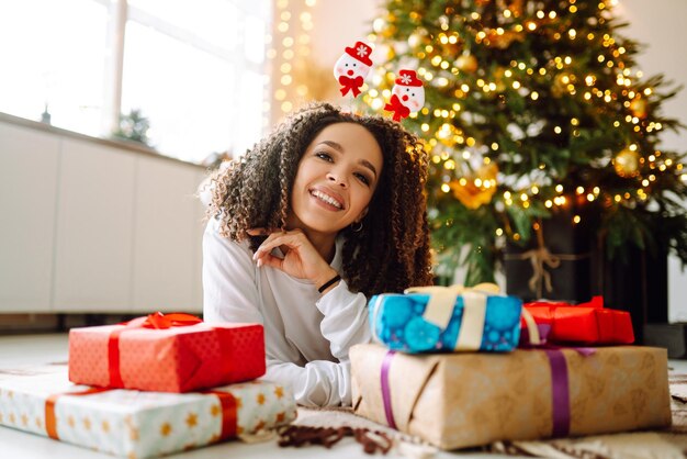 Retrato de jovem com chapéu de Papai Noel com presente na árvore de Natal Natal Ano Novo