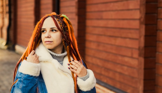 Retrato de jovem com dreadlocks de gengibre posando na rua da cidade Mulher positiva olhando para longe sorrindo