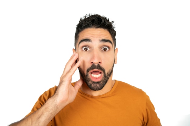 Retrato de jovem com expressão facial de choque e olhando surpreso para a câmera contra um fundo branco.