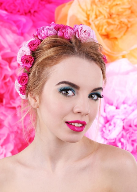 Retrato de jovem com flores no cabelo em fundo rosa brilhante