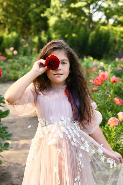 Retrato de jovem com flores no jardim. a menina cobriu os olhos com uma flor