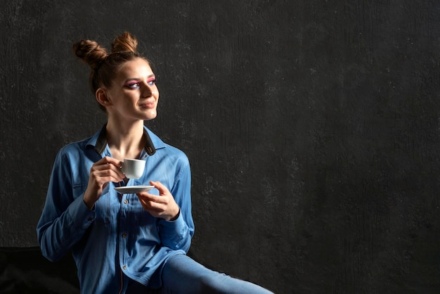 Retrato de jovem com penteado de coque e maquiagem de noite Copie o espaço Mulher com uma xícara de café em fundo preto