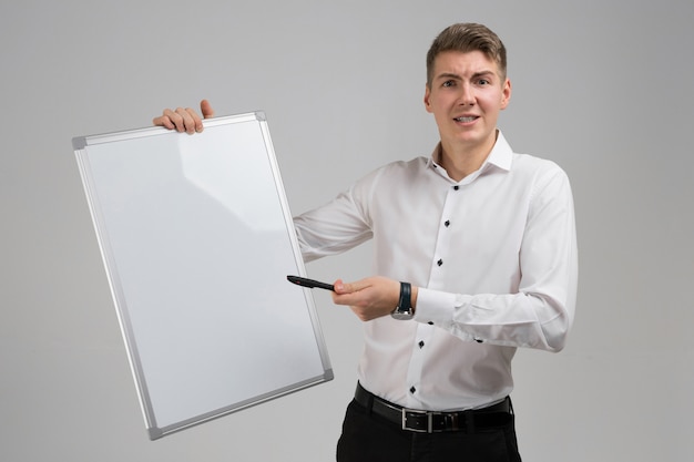 Retrato de jovem com placa magnética limpa e marcador nas mãos isolado no branco