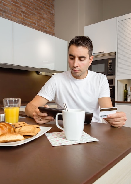 Retrato de jovem com tablet eletrônico, revisando pagamentos mensais de cartão de crédito. Conceito de banco eletrônico.