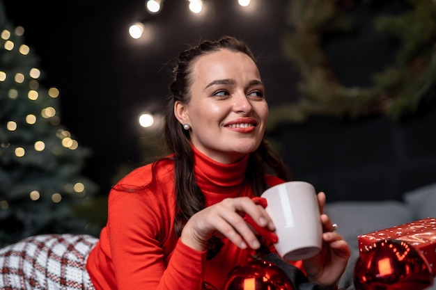 Retrato de jovem comemorando o ano novo Mulher muito sonhadora com árvore de natal