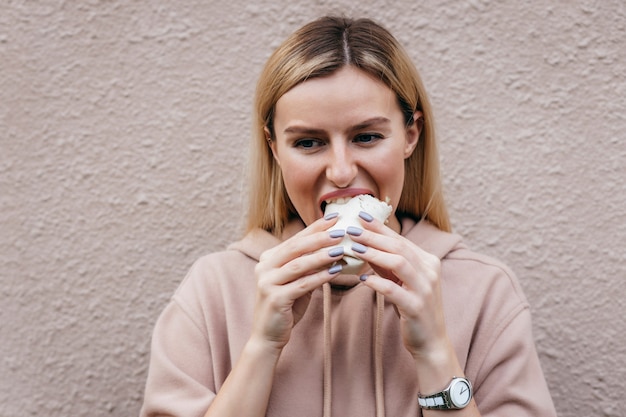 Retrato de jovem comendo frango enrolado na rua