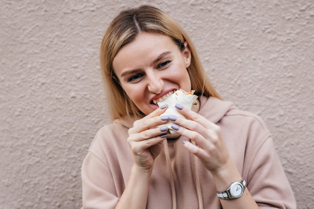 Retrato de jovem comendo frango enrolado na rua