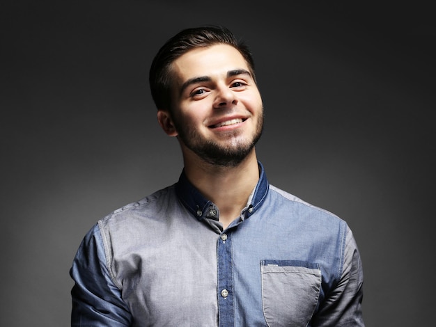 Retrato de jovem de camisa azul em fundo cinza