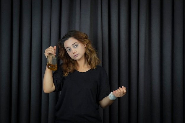 Retrato de jovem deprimido segurando a garrafa de álcool e olhando para a câmera. Foto de alta qualidade