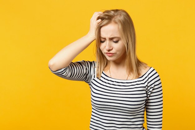 Retrato de jovem descontente em roupas listradas, mantendo os olhos fechados, colocando a mão na cabeça isolada no fundo da parede laranja amarela. Conceito de estilo de vida de emoções sinceras de pessoas. Mock up espaço de cópia.