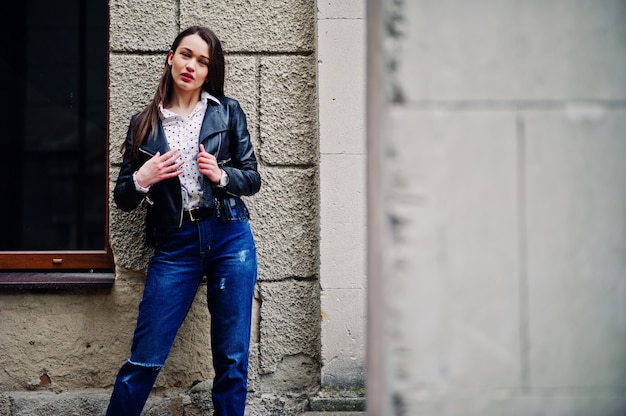 Foto retrato de jovem elegante vestindo jaqueta de couro e jeans rasgados nas ruas da cidade