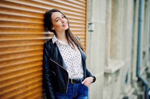 Foto retrato de jovem elegante vestindo jaqueta de couro e jeans rasgados nas ruas da cidade