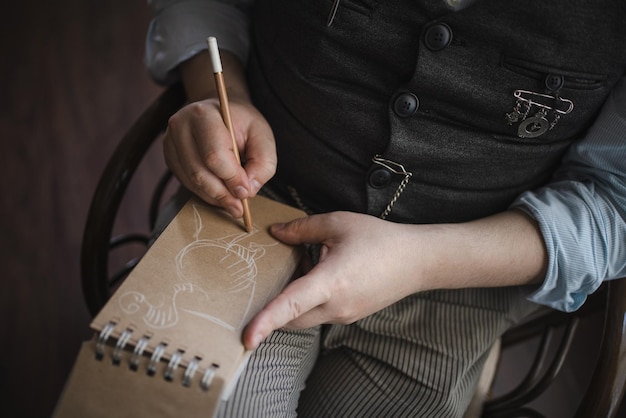 Retrato de jovem em colete de tweed e boné sentado com o bloco de notas no interior