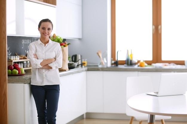 Foto retrato de jovem em pé com os braços cruzados contra o fundo da cozinha mulher na cozinha