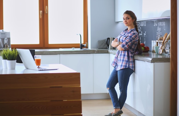 Retrato de jovem em pé com os braços cruzados contra o fundo da cozinha