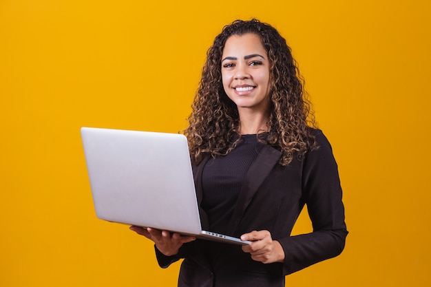 Retrato de jovem em roupa executiva com laptop em fundo amarelo. Mulher de negócios trabalhando com laptop