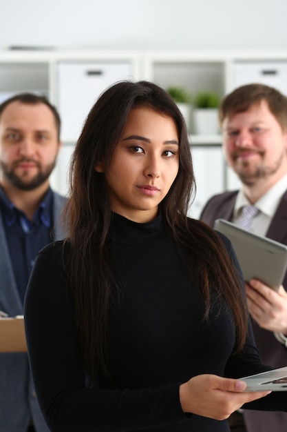 Foto retrato de jovem empresária bem sucedida segurar laptop e dois empresários no escritório