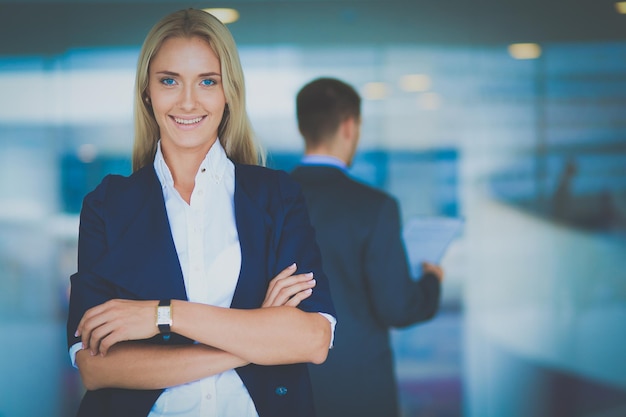 Retrato de jovem empresária no escritório com colegas ao fundo