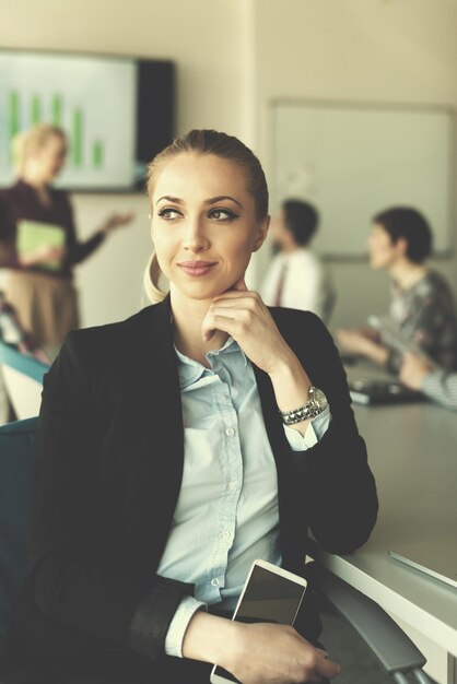 retrato de jovem empresária no interior do escritório de inicialização moderno, equipe em grupo de reunião em segundo plano