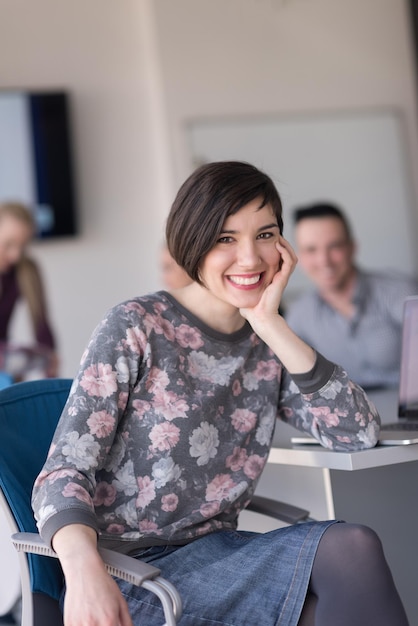 retrato de jovem empresária no interior do escritório de inicialização moderno, equipe em grupo de reunião em segundo plano