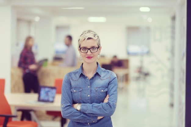 retrato de jovem empresária no interior do escritório de inicialização moderno, equipe em reunião em segundo plano