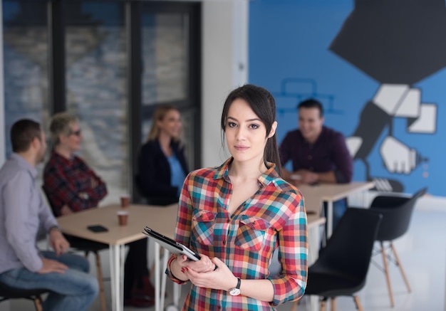 retrato de jovem empresária no interior do escritório de inicialização moderno, equipe em reunião em segundo plano