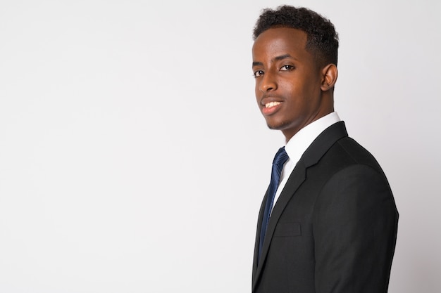 Retrato de jovem empresário africano com cabelo afro em um terno contra uma parede branca