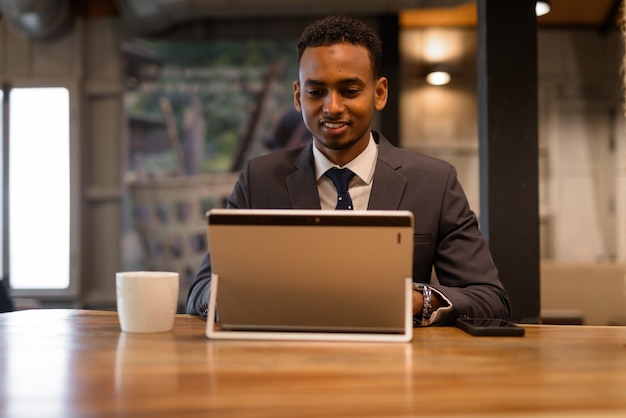 Retrato de jovem empresário africano relaxando dentro de uma cafeteria