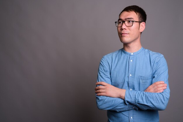 Retrato de jovem empresário asiático contra parede cinza