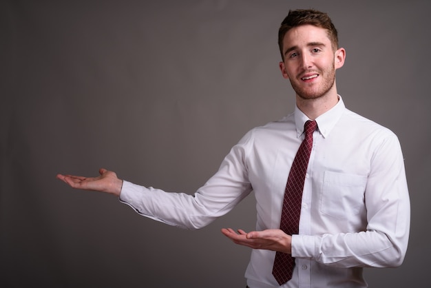 Retrato de jovem empresário bonito contra cinza