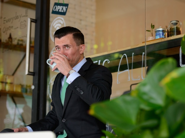 Retrato de jovem empresário bonito de terno no café ao ar livre