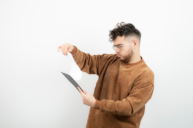 Retrato de jovem empresário bonito em copos, segurando o bloco de notas.
