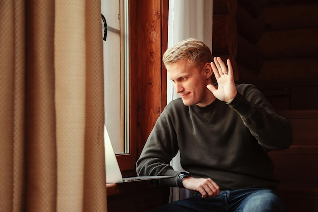 Retrato de jovem empresário com laptop na janela da sala de estar