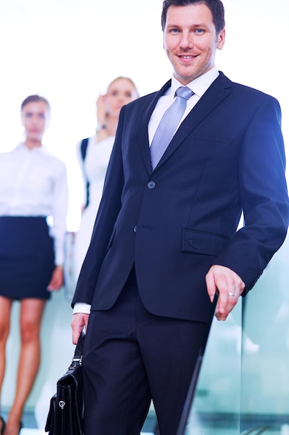 Retrato de jovem empresário no escritório com colegas ao fundo