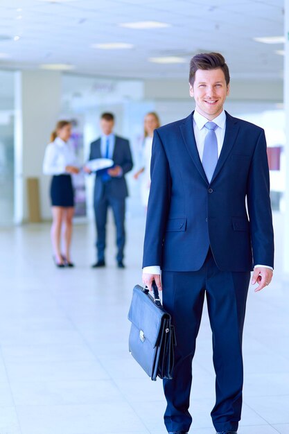 Retrato de jovem empresário no escritório com colegas em segundo plano Retrato de jovem empresário