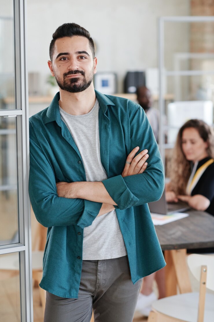 Foto retrato de jovem empresário olhando para a câmera enquanto trabalhava com seus colegas no escritório