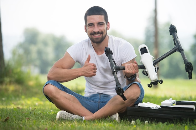 Retrato de jovem engenheiro confiante com controle remoto e drone dá polegares para cima