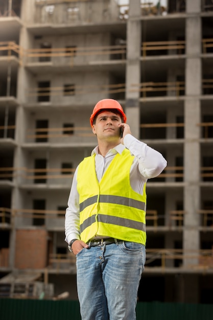 Foto retrato de jovem engenheiro de construção falando por telefone no canteiro de obras