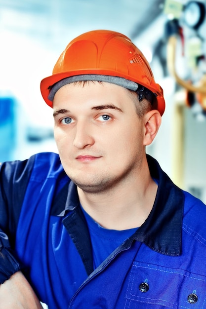 Retrato de jovem engenheiro em capacete em ambiente de trabalho na fábricaTrabalhador de gás olha com confiança diretamente para a câmera