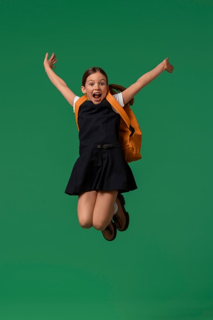 Foto retrato de jovem estudante em uniforme escolar pulando no ar