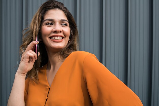 Retrato de jovem falando ao telefone em pé ao ar livre na rua