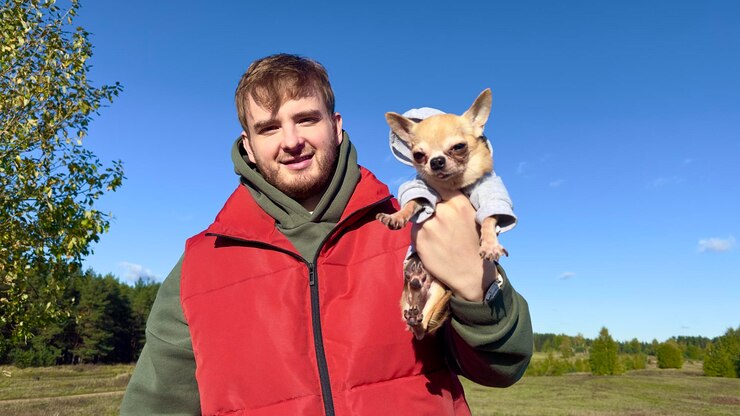 Foto retrato de jovem feliz com seu cachorro chihuahua segurando em mãos um cachorrinho em fundo natural
