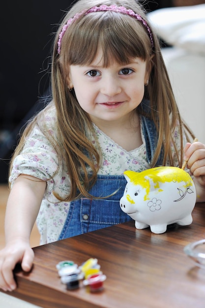 retrato de jovem feliz em casa enquanto pintava o cofrinho e representava o conceito de banco e finanças