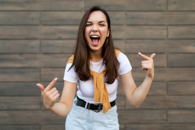 Retrato de jovem feliz, positiva, linda morena, com emoções sinceras, vestindo roupas elegantes