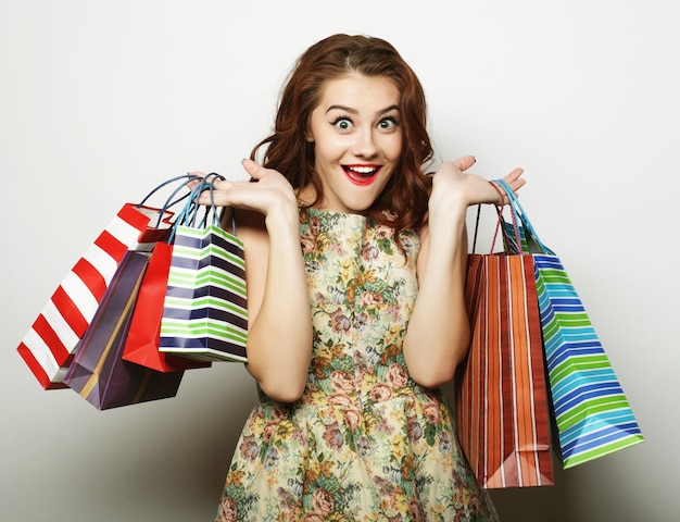 Retrato de jovem feliz sorridente com sacos de compras sobre fundo branco