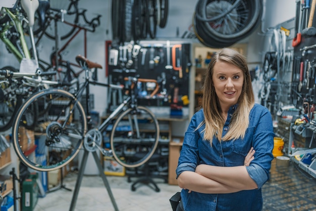 Retrato, de, jovem, femininas, mecânico, em, loja bicicleta