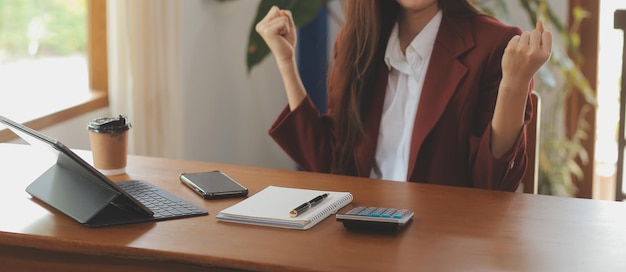 Retrato de jovem freelancer de mão asiática está trabalhando em seu trabalho em tablet de computador em escritório moderno Fazendo relatório de análise contábil dados de investimento imobiliário Conceito de sistemas financeiros e fiscais