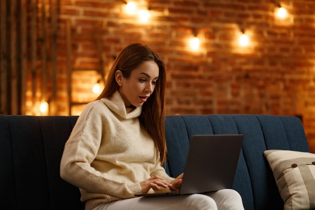 Retrato de jovem freelancer feminino usando laptop e sorrindo