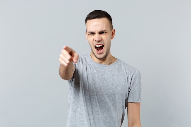 Retrato de jovem gritando com raiva em roupas casuais xingando, apontando o dedo indicador para a frente